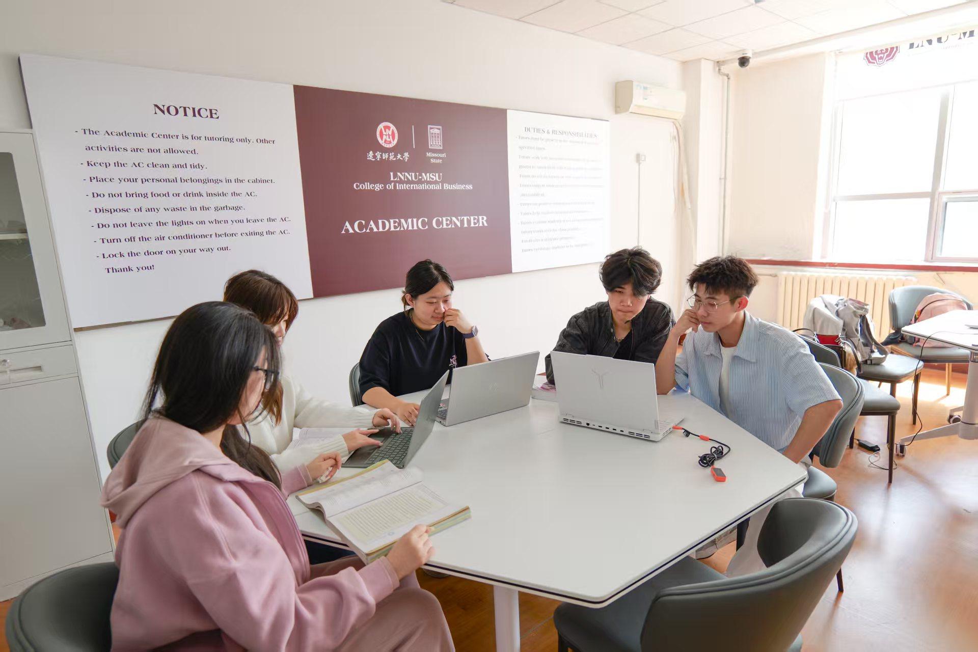 5 students sitting in a classroom environment having laptops with them.